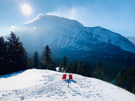 Winter mountain view with red chairs overlooking a snowy peak